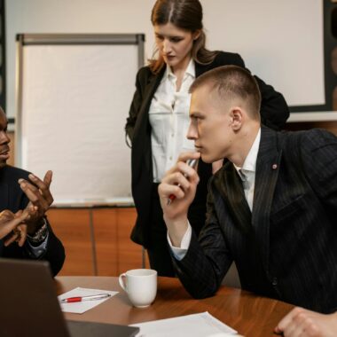 Diverse colleagues in active discussion around a conference table in a modern office setting.